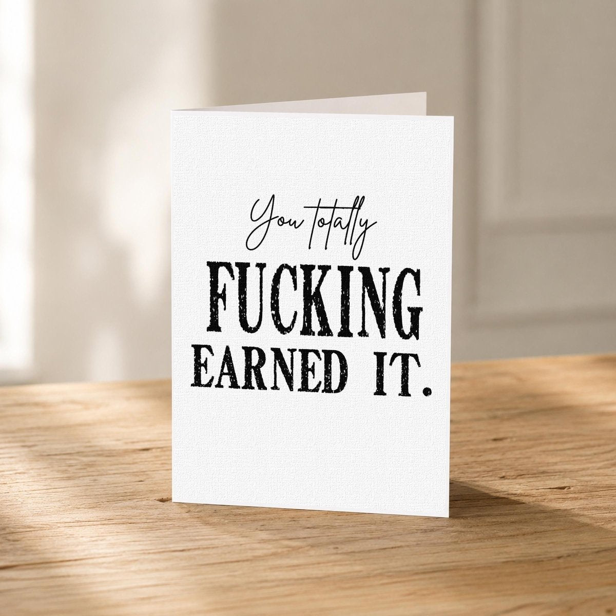 Close-up of the Totally Earned It Funny Graduation Card showing the bold black lettering.