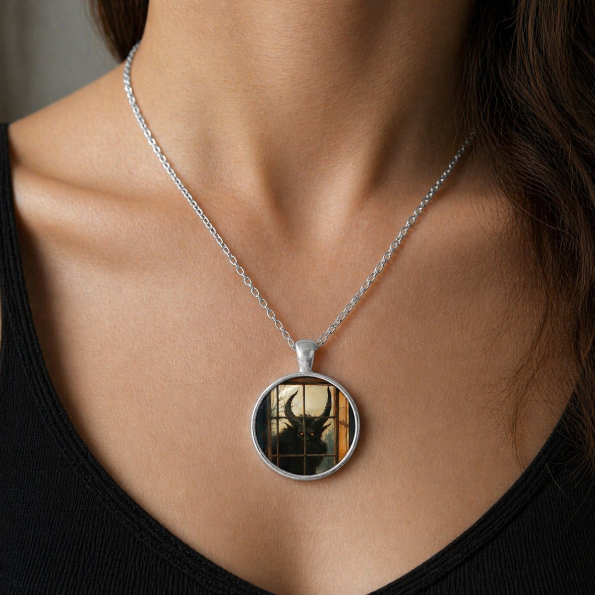 A silver necklace with a circular pendant featuring a silhouette of a person's face.
