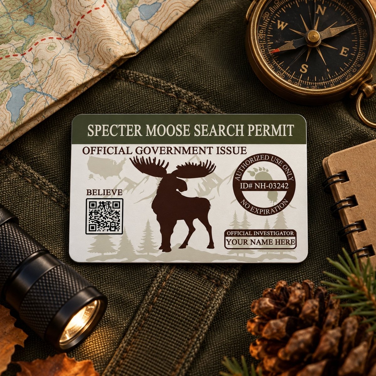 a "Spepper Moose Search Permit" card with a silhouette of a moose, placed on top of a map, compass, and other outdoor gear.