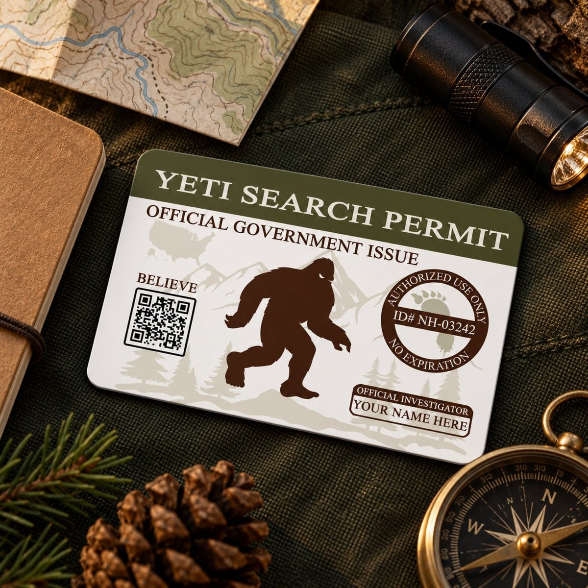 a YETI SEARCH PERMIT, a government-issued permit, with a bear silhouette and a QR code, placed on a surface with a compass, pine cone, and flashlight.