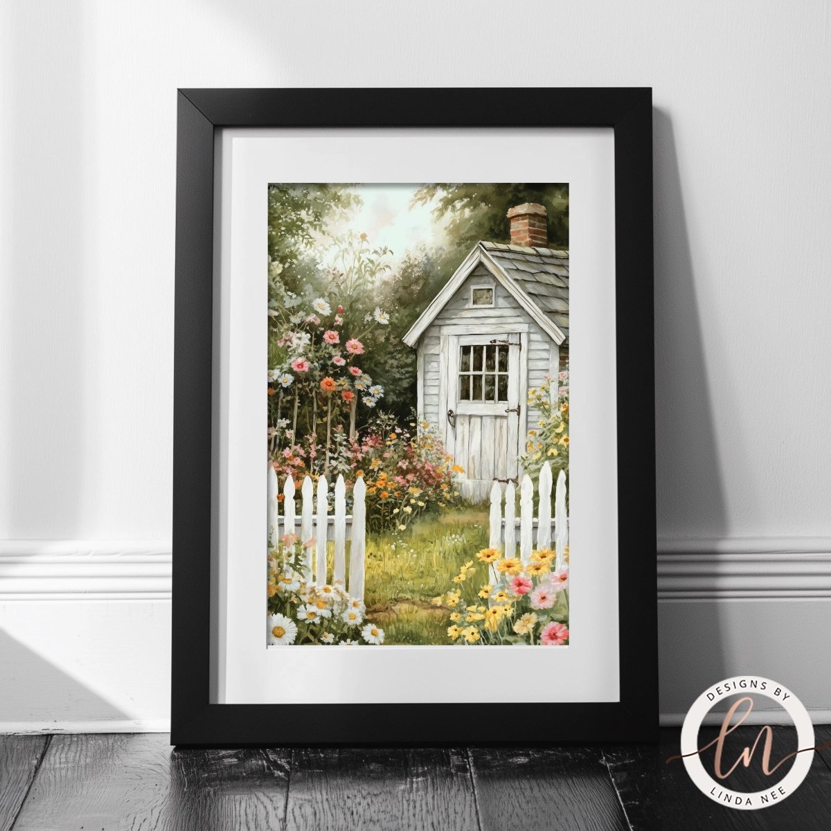 A framed print depicting a charming garden scene with a quaint white shed surrounded by a lush garden filled with colorful flowers.