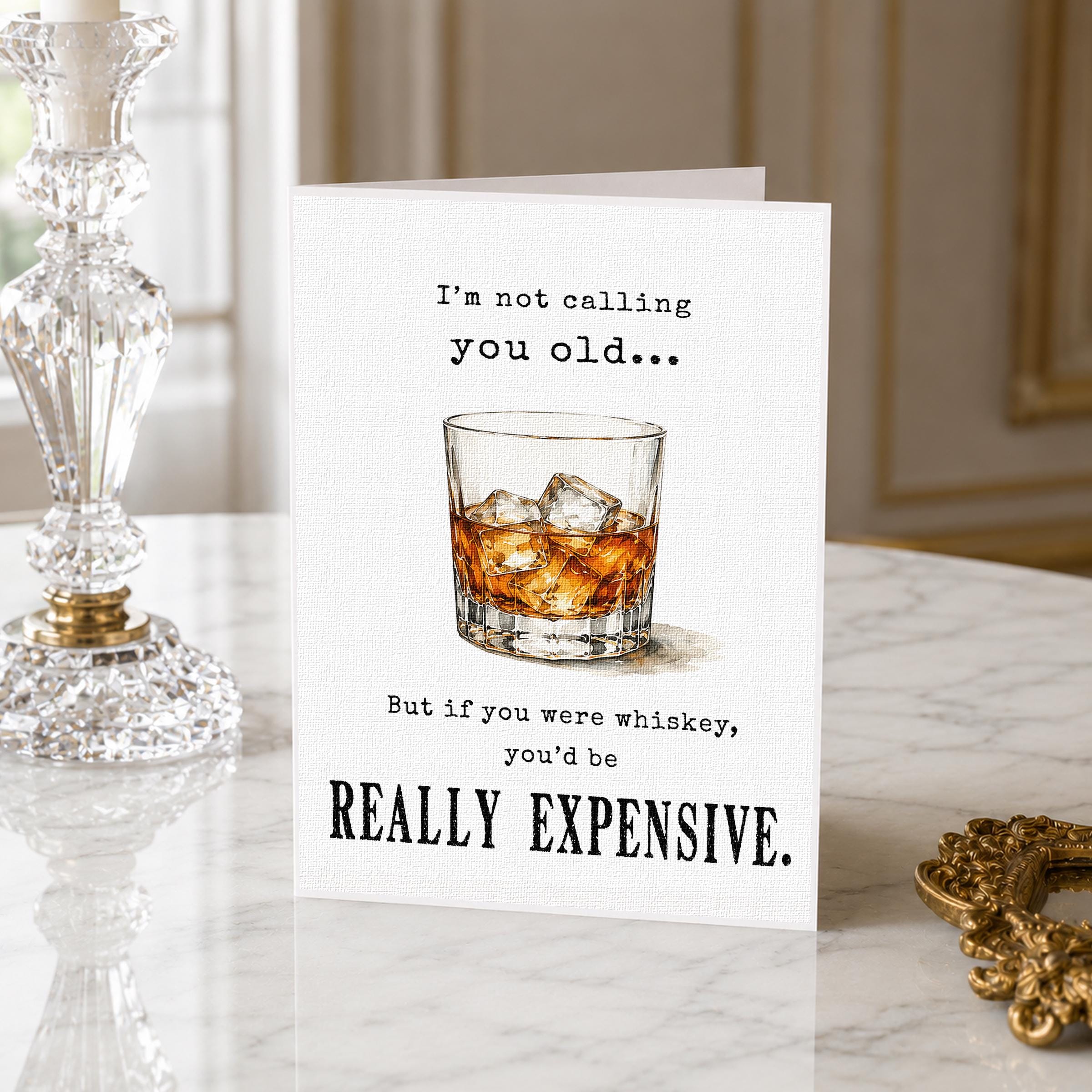 a card with a humorous message about whiskey, placed on a marble surface next to a crystal vase.