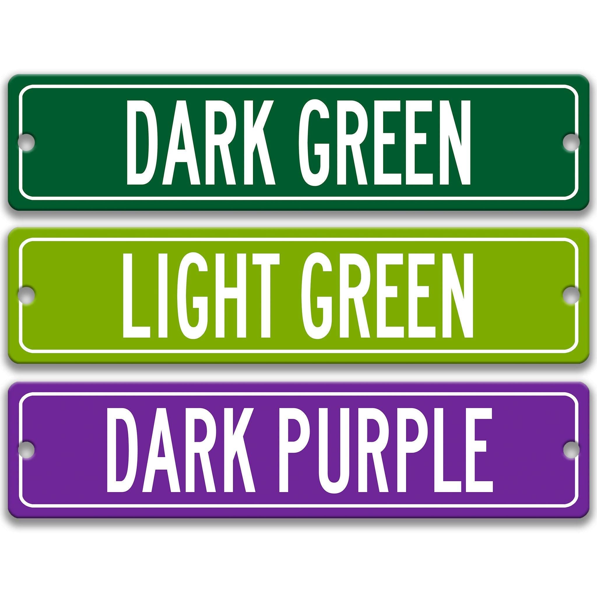three rectangular street signs with different colors: green, light green, and purple.