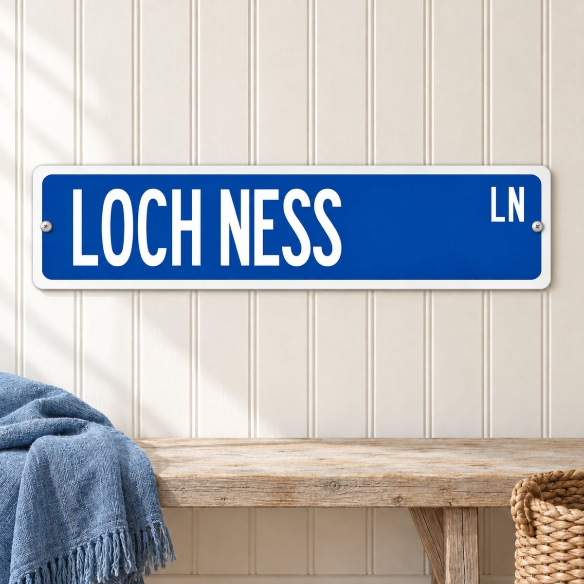 Loch Ness street sign with a blue background reading LOCH NESS LN, hanging on a wall