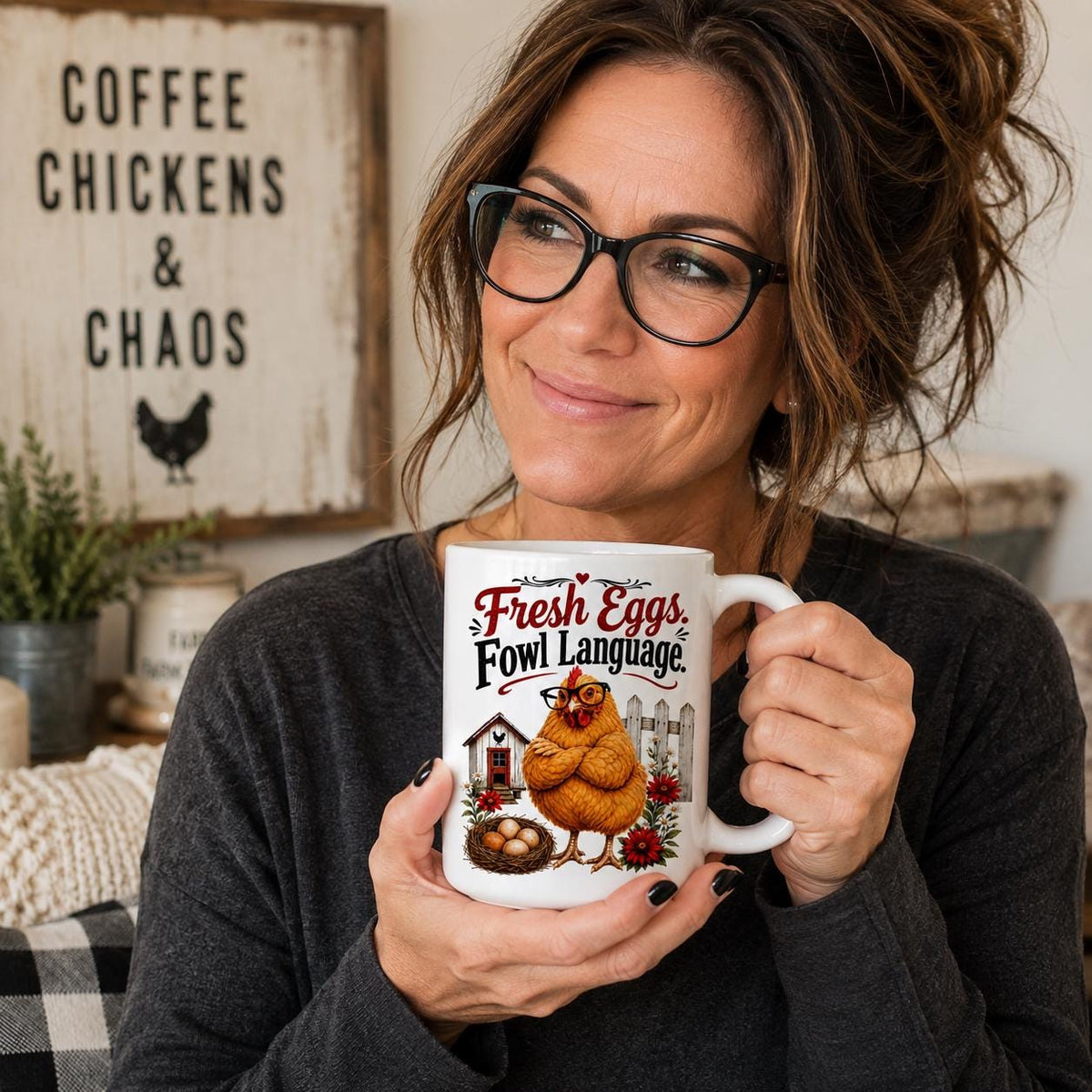 Smiling woman in glasses holding the grumpy hen mug in a farmhouse kitchen with a coffee and chickens sign