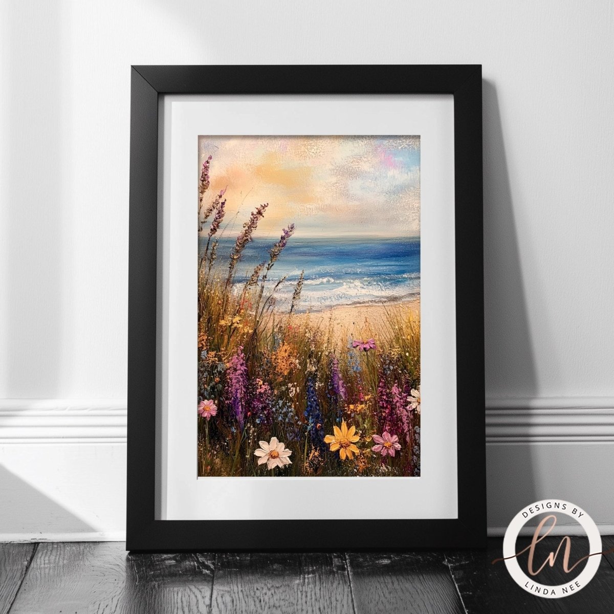 A framed painting depicting a vibrant coastal scene with a field of colorful wildflowers in the foreground and the ocean in the background.
