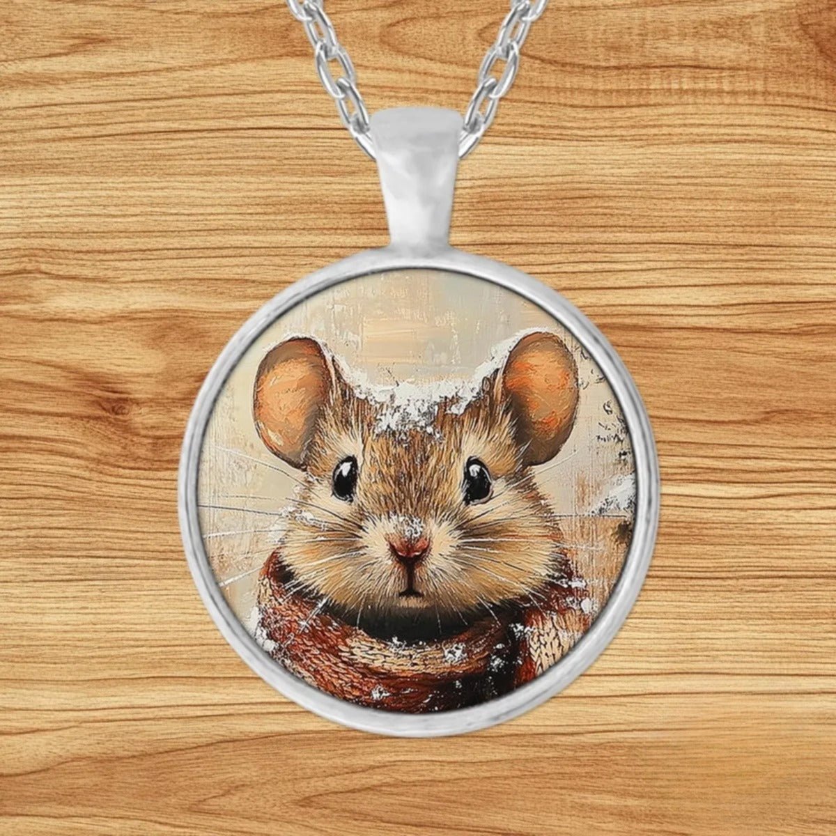 Round silver charm pendant necklace featuring a mouse bundled in a plaid scarf in a snowy forest with a frosted pinecone