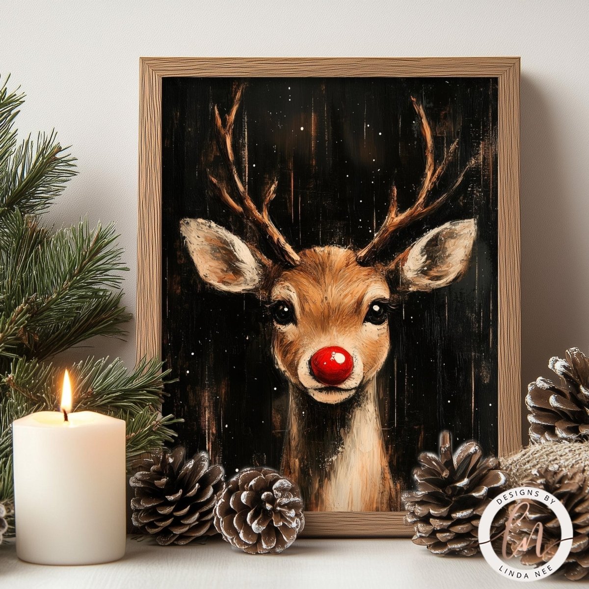 A framed painting of a reindeer with a red nose is displayed on a shelf, surrounded by pine cones and a lit candle, creating a festive holiday scene.
