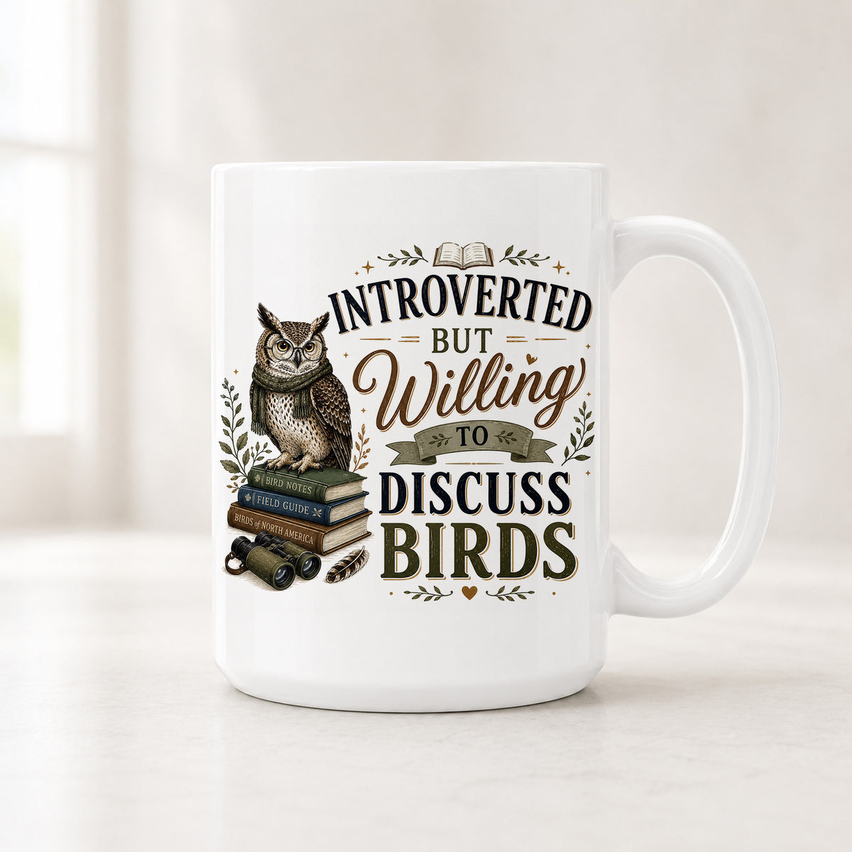 Second view of the white owl mug with binoculars, a feather and field guides beside brown and navy lettering