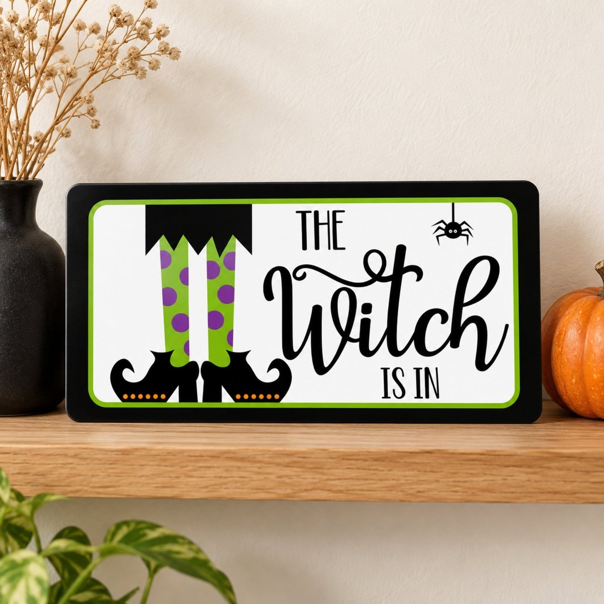 The Witch Is In sign on a shelf with fall decor