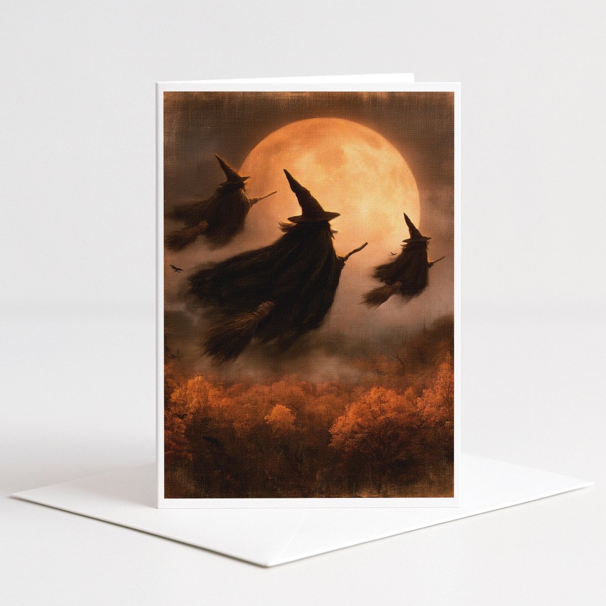Three witches flying in silhouette across a glowing orange harvest moon, Halloween note card art