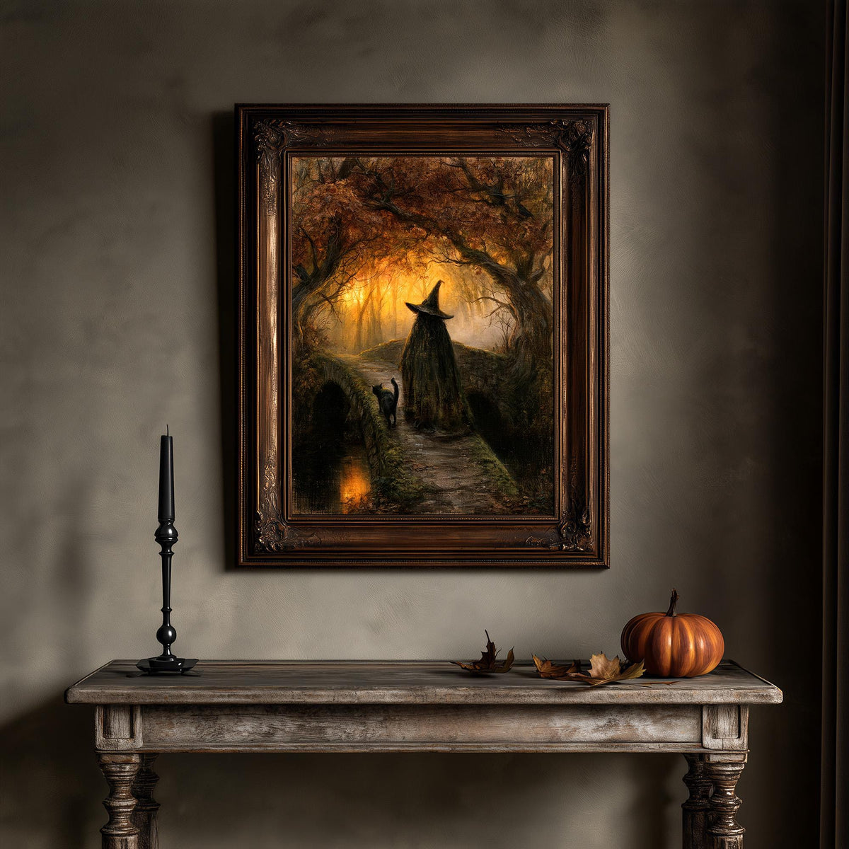 Black cat wall art hung above a wooden console with a pumpkin and a single candle