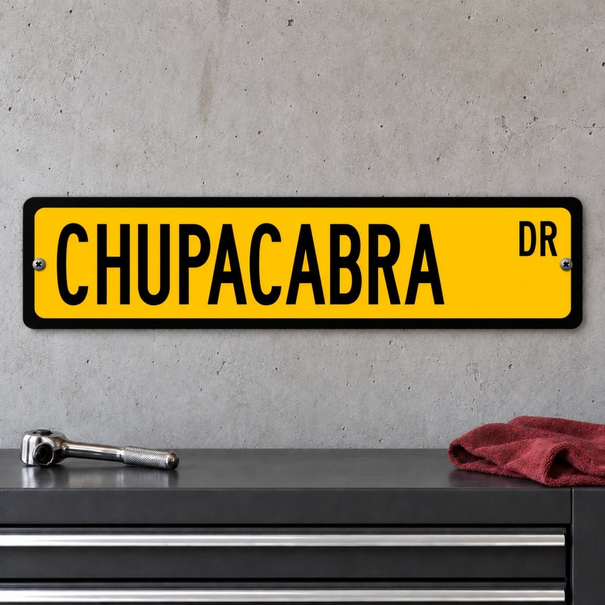 Chupacabra street sign with a yellow background reading CHUPACABRA DR, hanging on a wall
