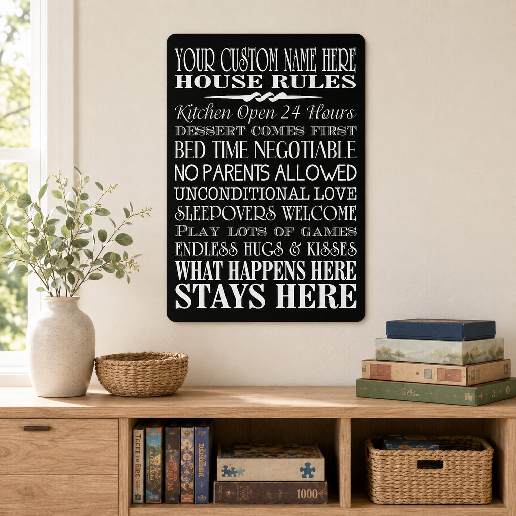 a black sign with white text hanging on a wall, placed above a wooden bookshelf with a vase of flowers and a stack of books.