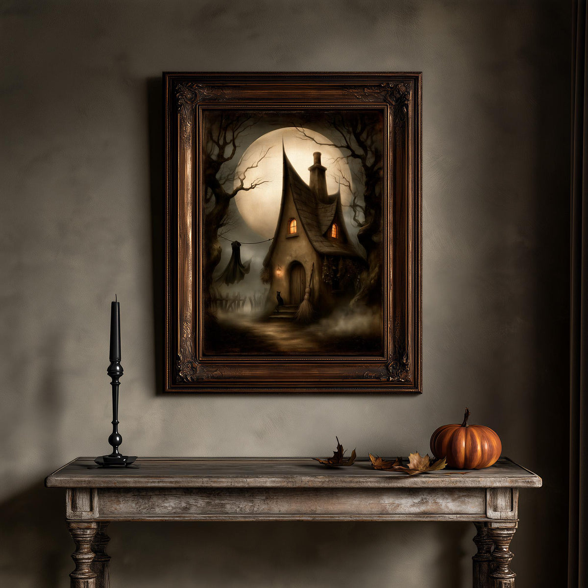 Moonlit cottage wall art above a table holding a candle and a pumpkin