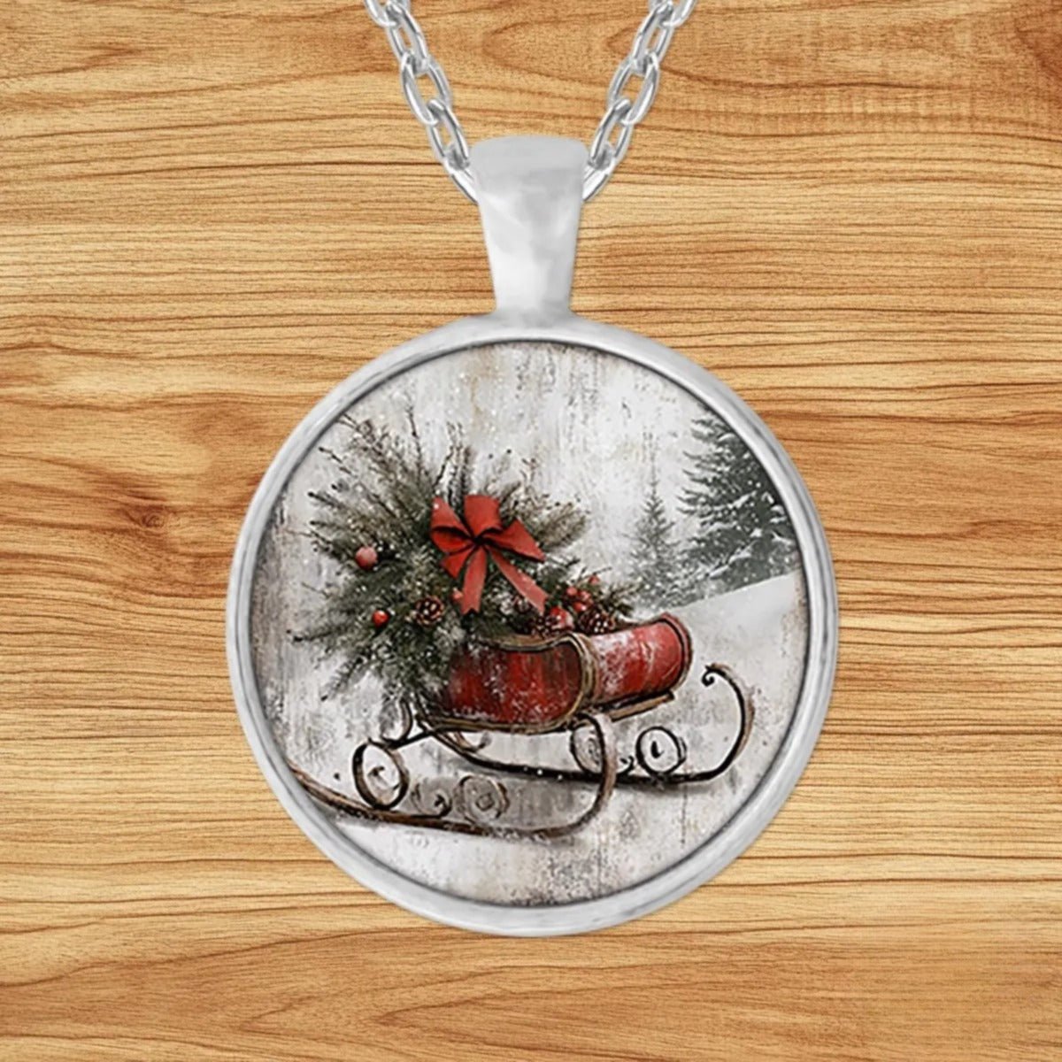 Round silver charm pendant necklace featuring a red wooden sled loaded with a fresh-cut Christmas tree tied with a bow