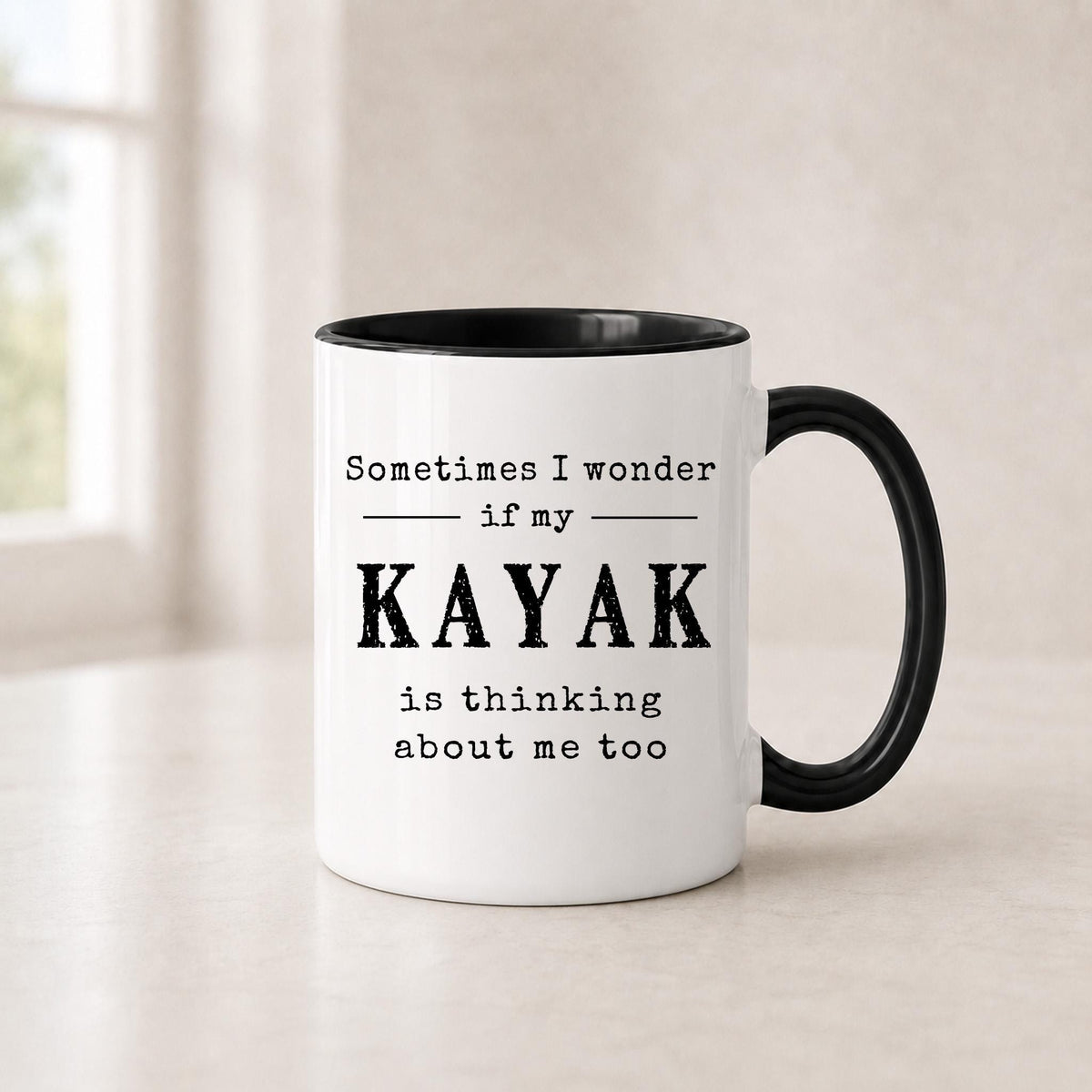Kayak quote mug in the 11 oz black handle version, white ceramic with black lettering on a light surface