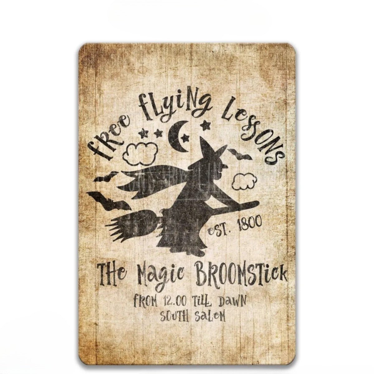 The image is a sign with a distressed wood look, featuring a witch on a broomstick and the text "Free Flying Lessons" and "The Nagie Broomstick" along with the establishment year of 1800.