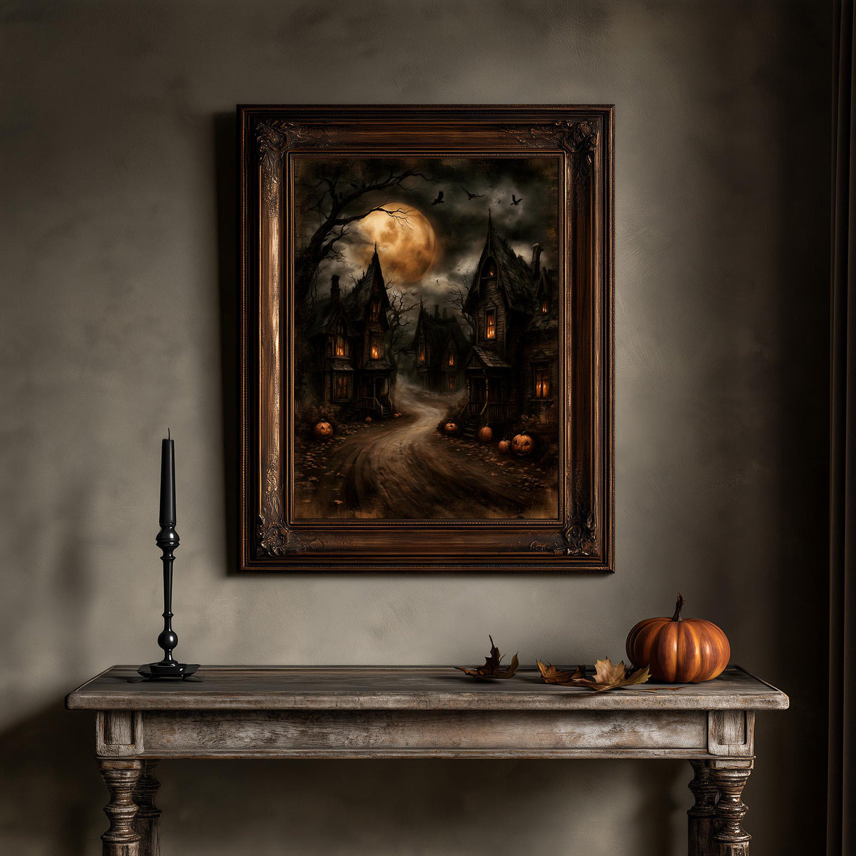Haunted village wall art above a table holding a pumpkin and a lit candle