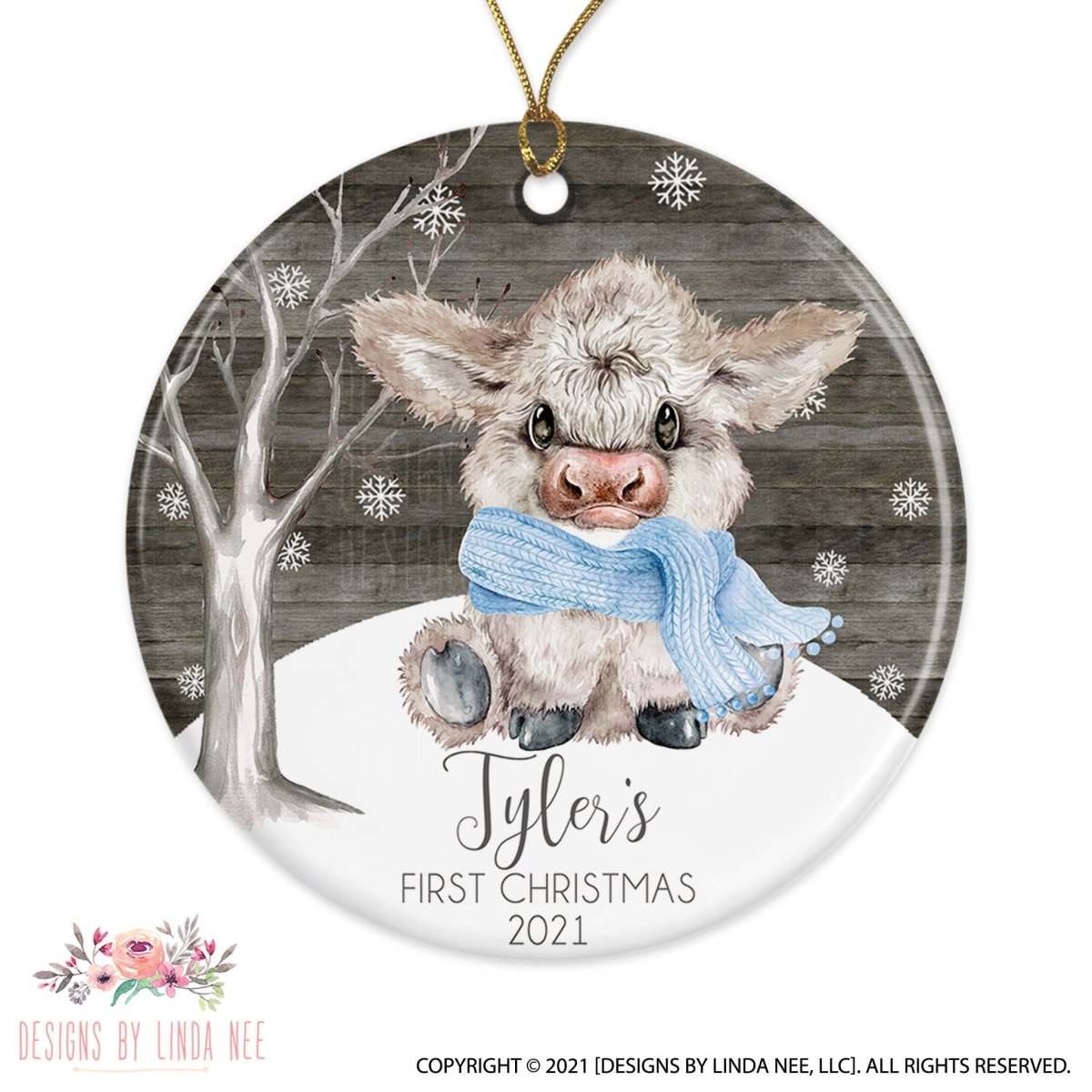 A ceramic ornament featuring a cute cow wearing a blue scarf and sitting on a snowy hill. The ornament has a text that reads " Tyler's FIRST CHRISTMAS 2021".