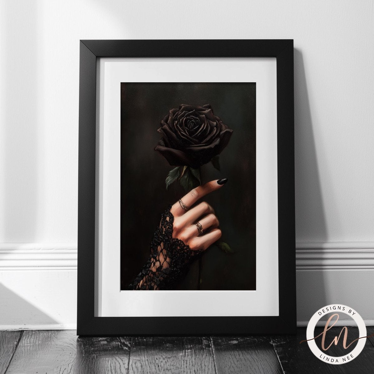 Framed artwork of a hand holding a black rose against a dark background.