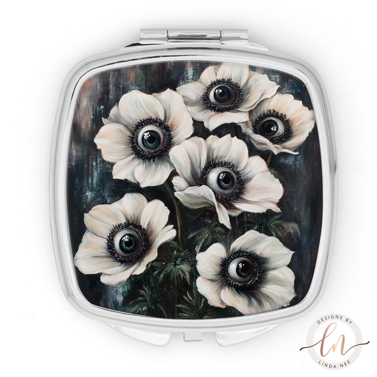 A square compact mirror with a floral design featuring white and black flowers with large, round eyes.