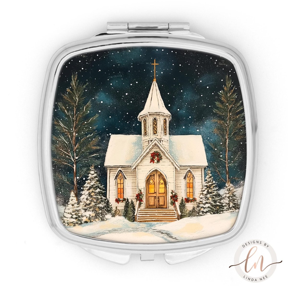 A square-shaped compact mirror with a winter scene of a church with a cross on top, surrounded by snow-covered trees and a starry night sky.
