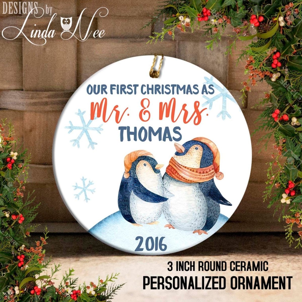 A round ceramic ornament with a couple of penguins wearing winter hats, surrounded by snowflakes and greenery. The text on the ornament reads "OUR FIRST CHRISTMAS AS MR. & MRS. THOMAS 2016 3 INCH ROUND CERamic PERSONALIZED ORNAMENT".