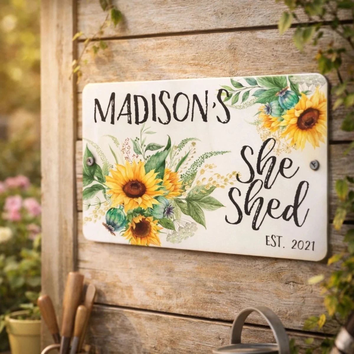 A wooden sign with a floral design and the name "Madison's She Shed" is displayed on a wooden wall.