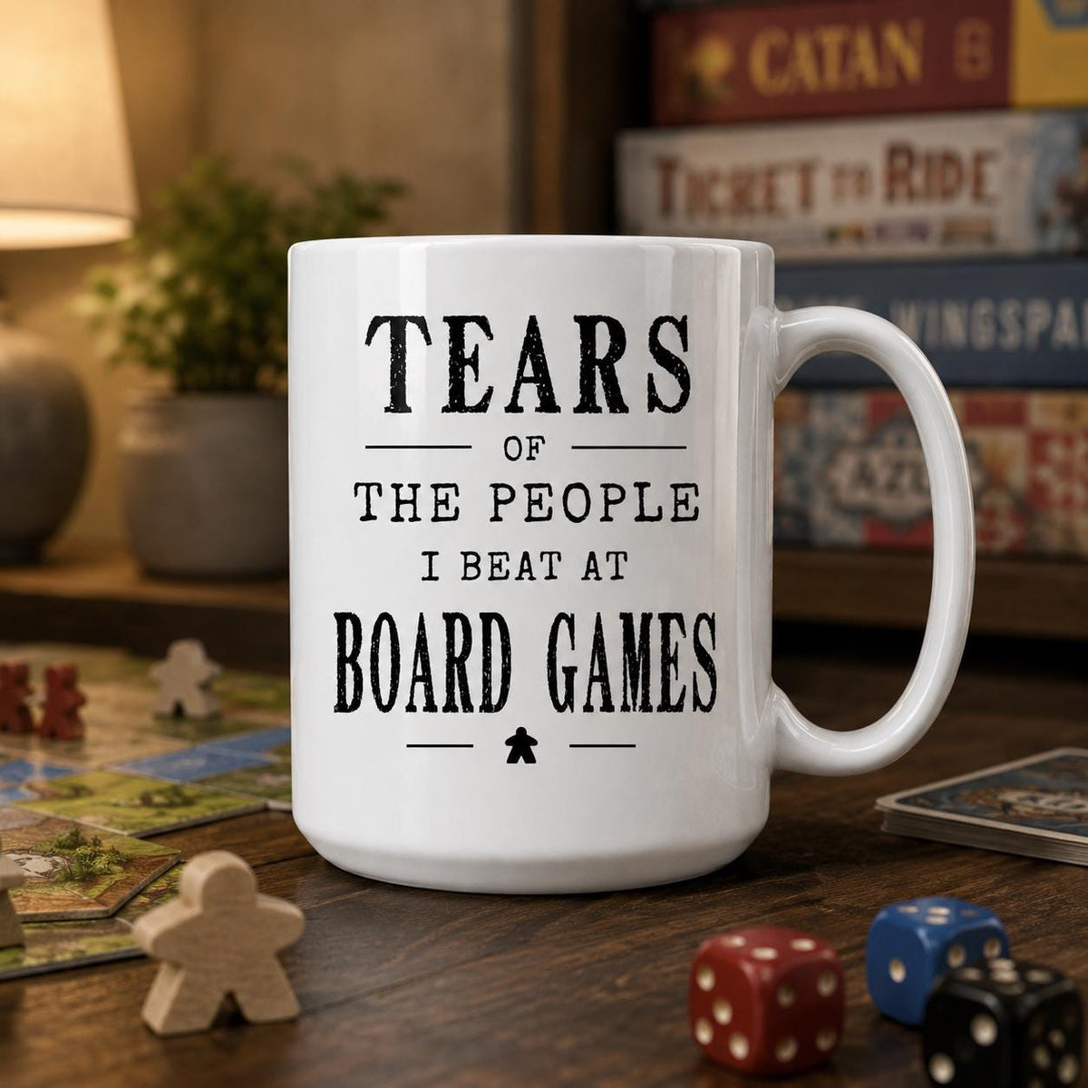 Board game mug surrounded by stacked board games and loose dice on a wooden table top