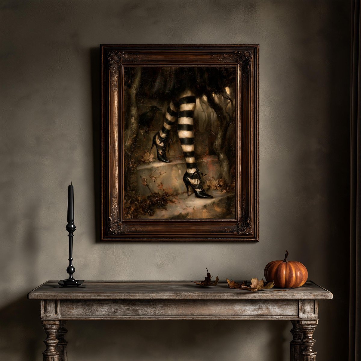 Witch legs wall art above a wooden table holding a candle and a small pumpkin