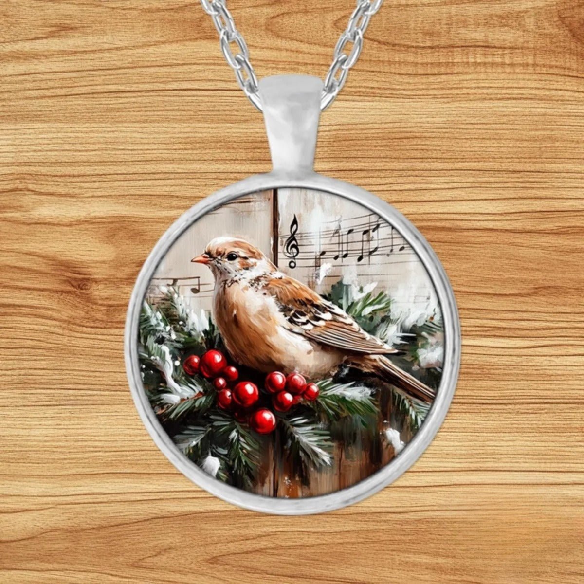 Round silver charm pendant necklace featuring a white dove perched on a pine branch with red berries over vintage sheet music