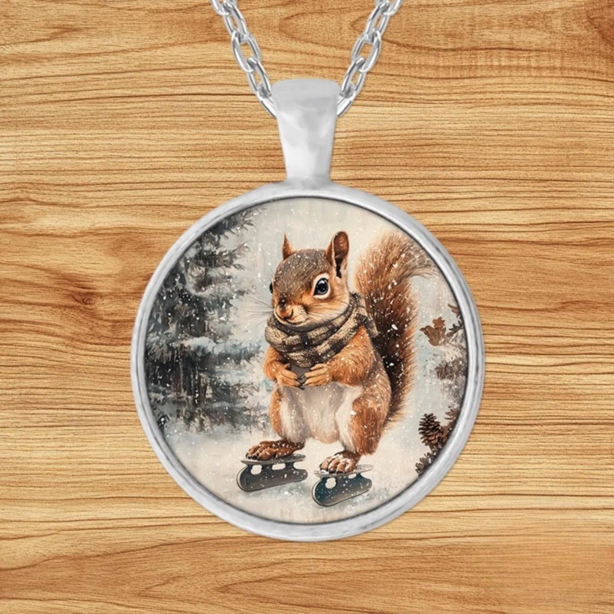 Round silver charm pendant necklace featuring a plaid-scarf squirrel ice skating across a frozen pond in a snowy pine forest