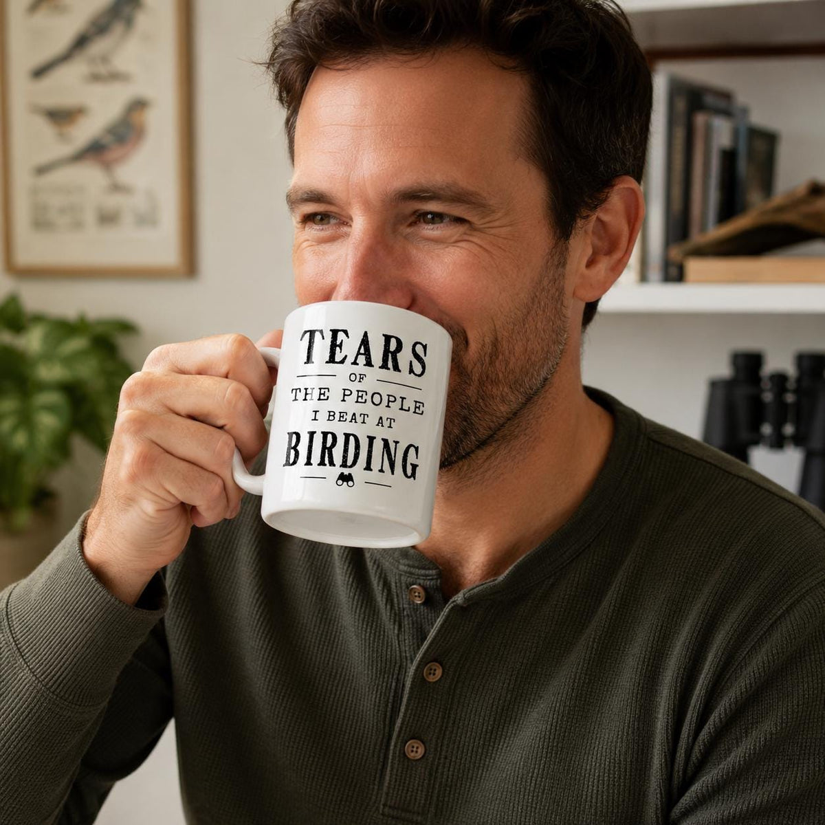 Man holding the Tears of the People I Beat at Birding mug, the black quote facing the camera