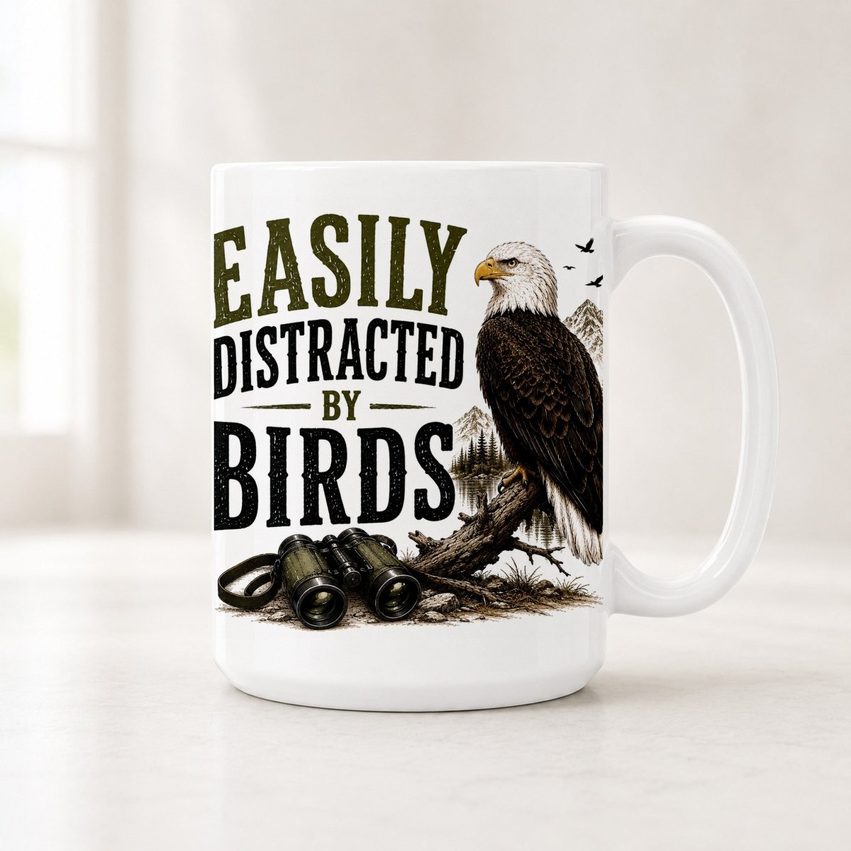 Second view of the white bald eagle mug with olive and black block lettering and pine trees behind the bird