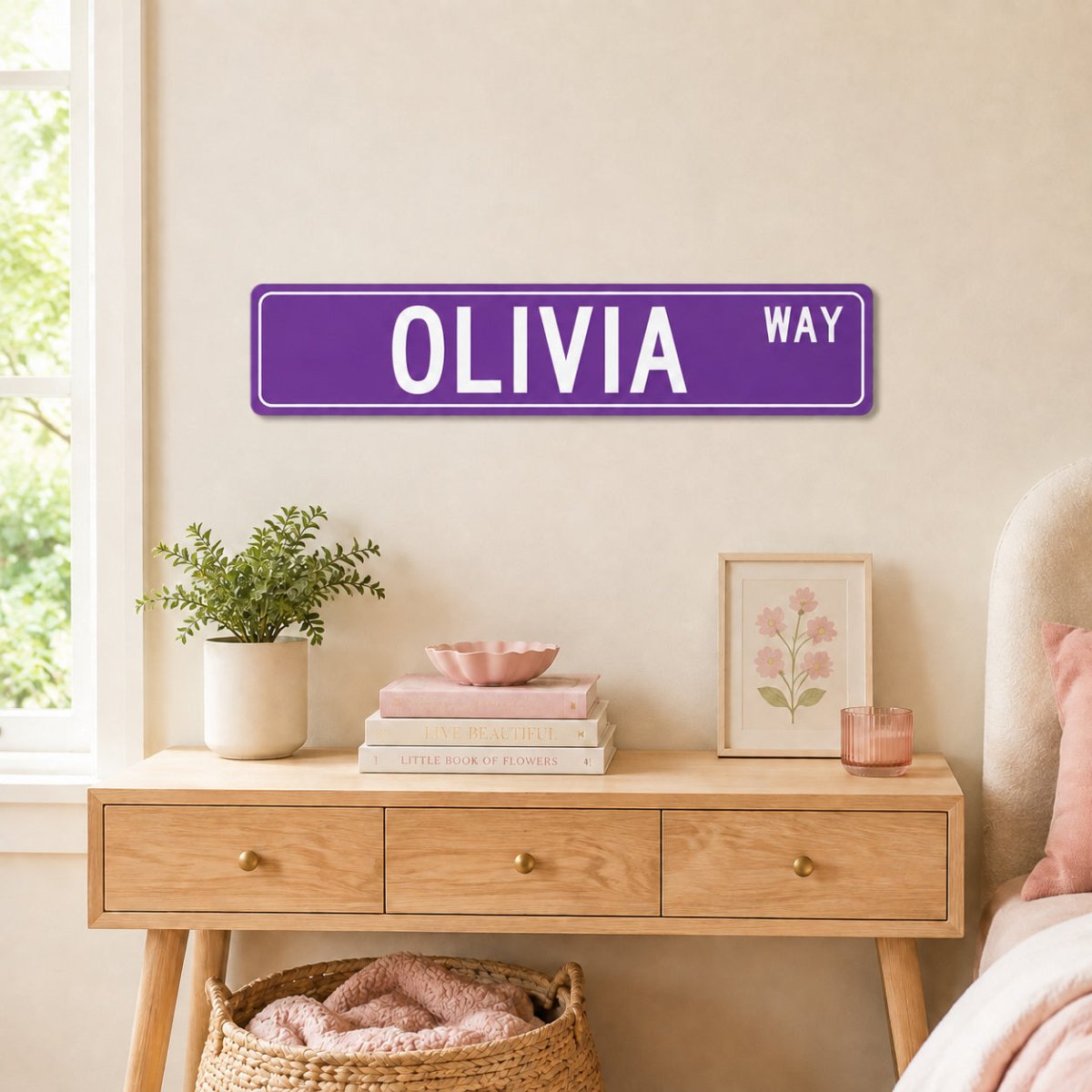 a bedroom setting with a purple street sign that reads "OLIVIA WAY" mounted on the wall above a wooden dresser. The dresser has various items on it, including a plant, books, and a framed picture.