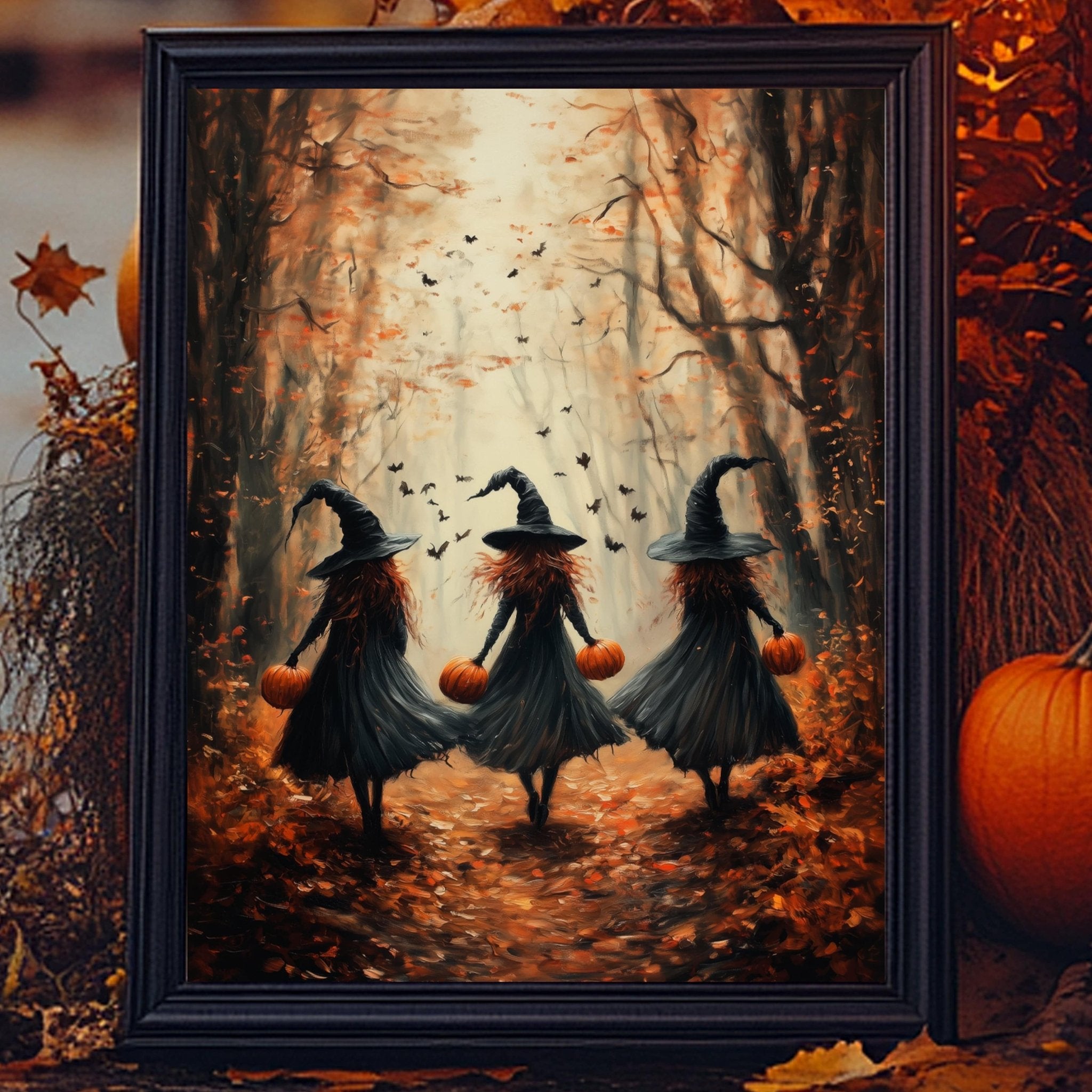 A framed painting depicting three women dressed as witches walking through a forest with autumn leaves and pumpkins in the background.