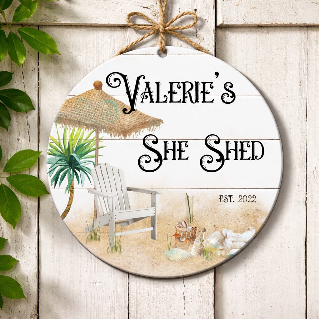 A round wooden sign with a beach scene, featuring a straw umbrella, a beach chair, and palm trees.