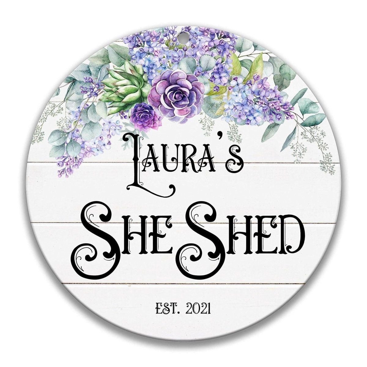 A round sign with a floral design and the text "Lauren's She Shed" printed on it.
