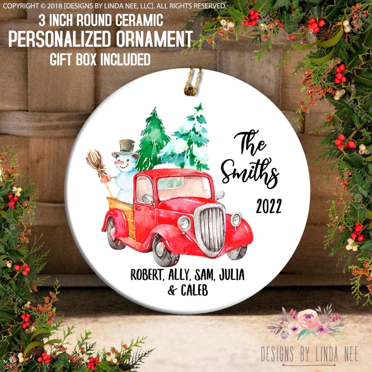 a ceramic ornament with a red truck and a snowman, surrounded by holiday decorations such as berries and greenery.