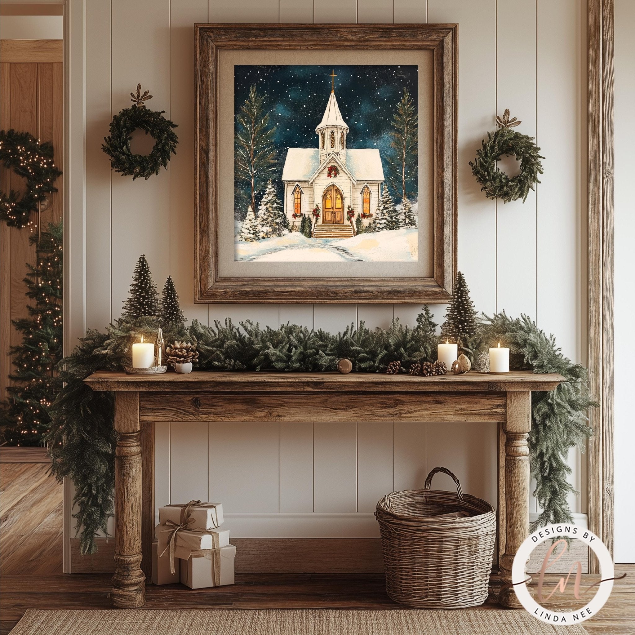 a cozy and festive Christmas scene, with a framed painting of a snowy church surrounded by pine trees and greenery. The painting is hung on a wall above a wooden console table, which is decorated with a garland, candles, and other holiday items. The overall atmosphere of the scene is warm and inviting, with the combination of the painting, candles, and other decorations creating a harmonious and visually appealing display.