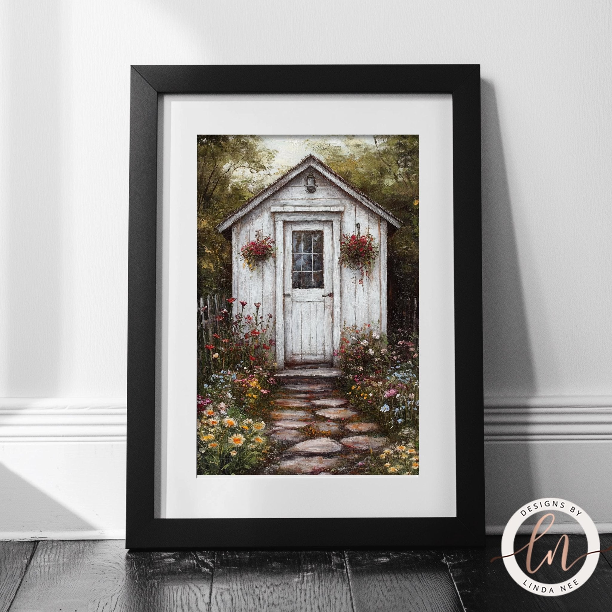 A framed painting depicting a quaint white wooden shed surrounded by a lush garden filled with colorful flowers and plants.