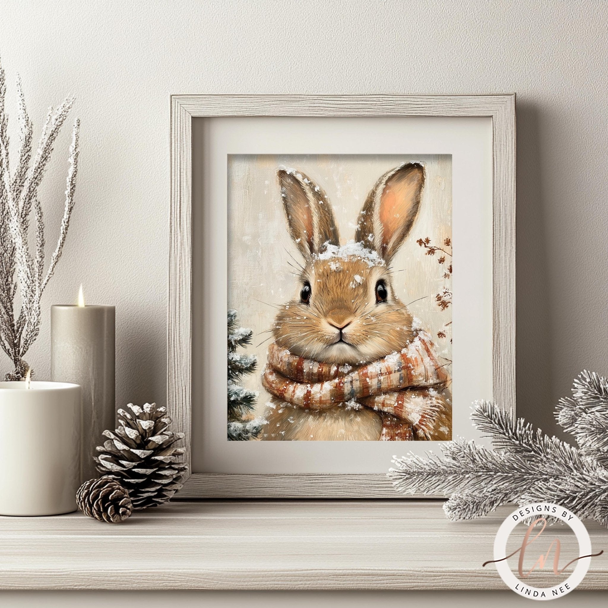 A framed print of a rabbit wearing a scarf and surrounded by snow and pine cones is displayed on a shelf, with a lit candle and pine cone nearby.