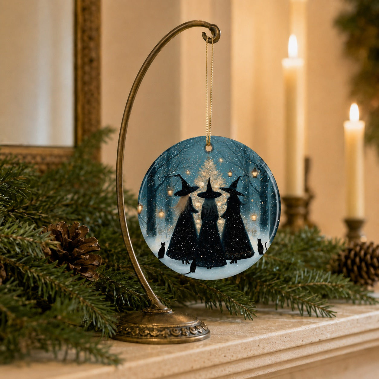Round witches Christmas ornament with a gold hanging cord displayed on a brass stand in a cozy holiday mantel setting.