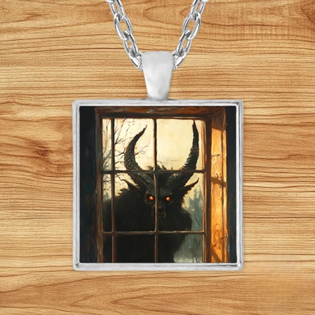Square silver charm pendant necklace featuring horned Krampus peering through a frost-etched window on a snowy Alpine night