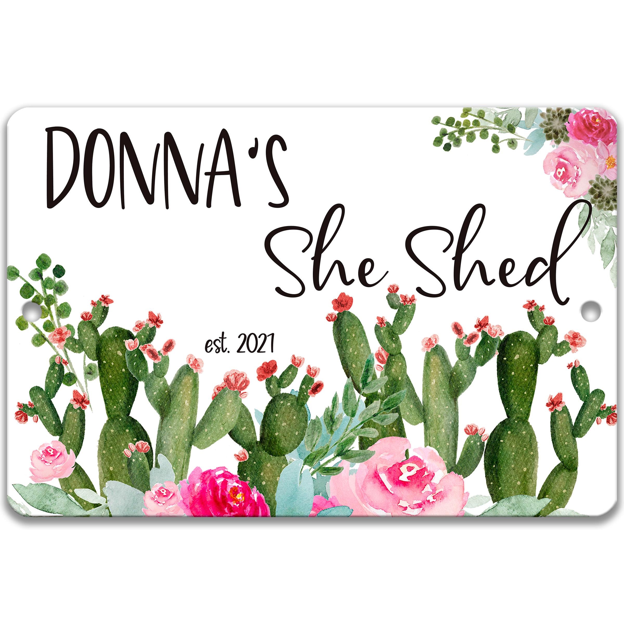 a sign with a floral design and the text "DONNA'S She Shed est. 2021".
