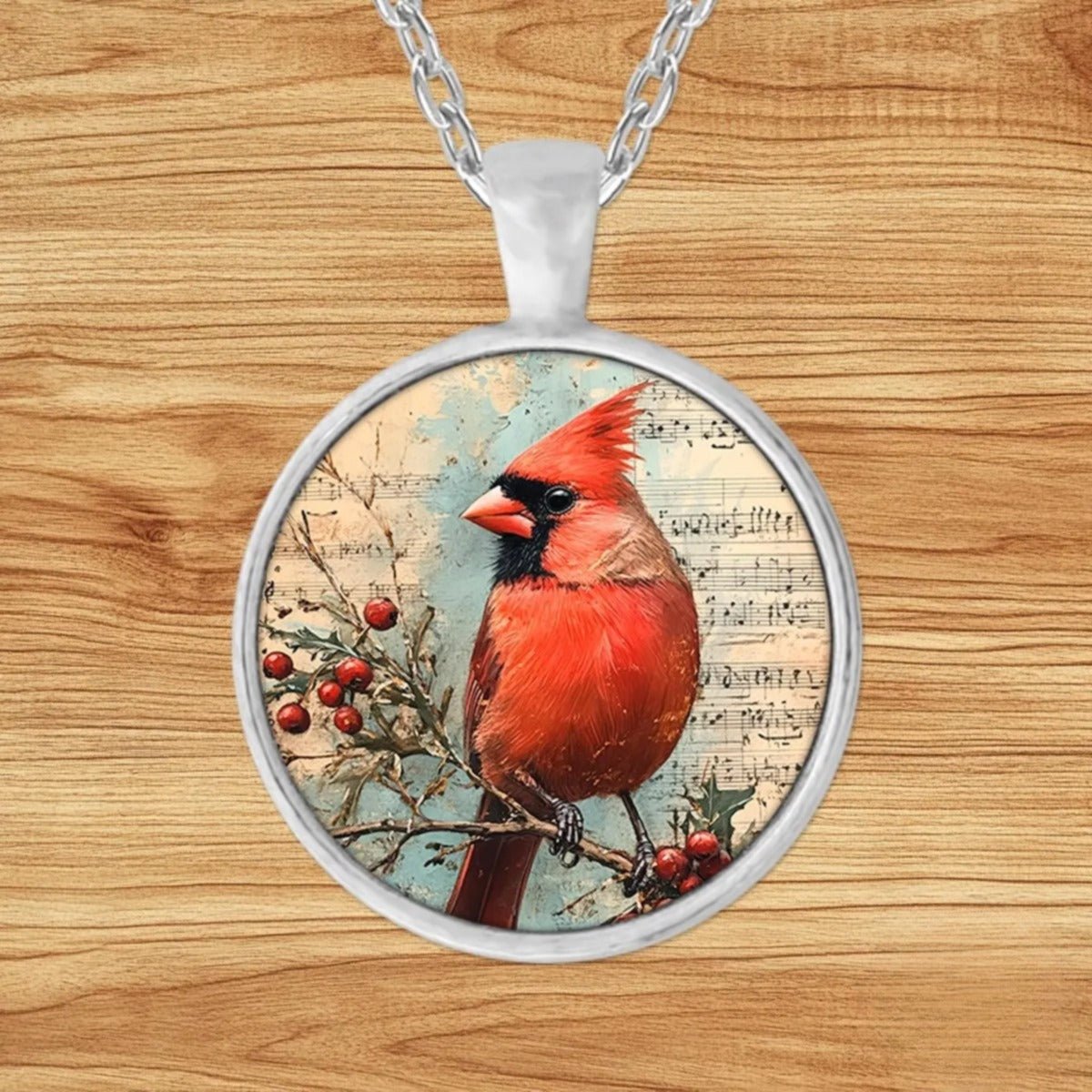 Round silver charm pendant necklace featuring a vivid red cardinal perched on a holly branch over vintage sheet music