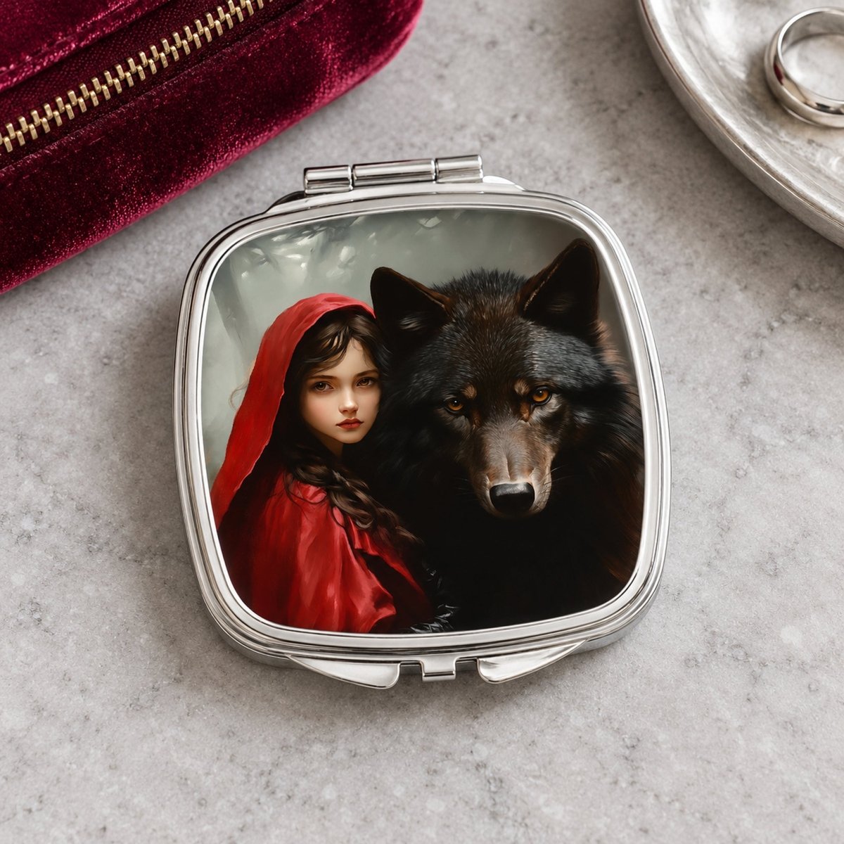 A compact mirror with a picture of a woman in a red hooded cloak and a wolf on the front.