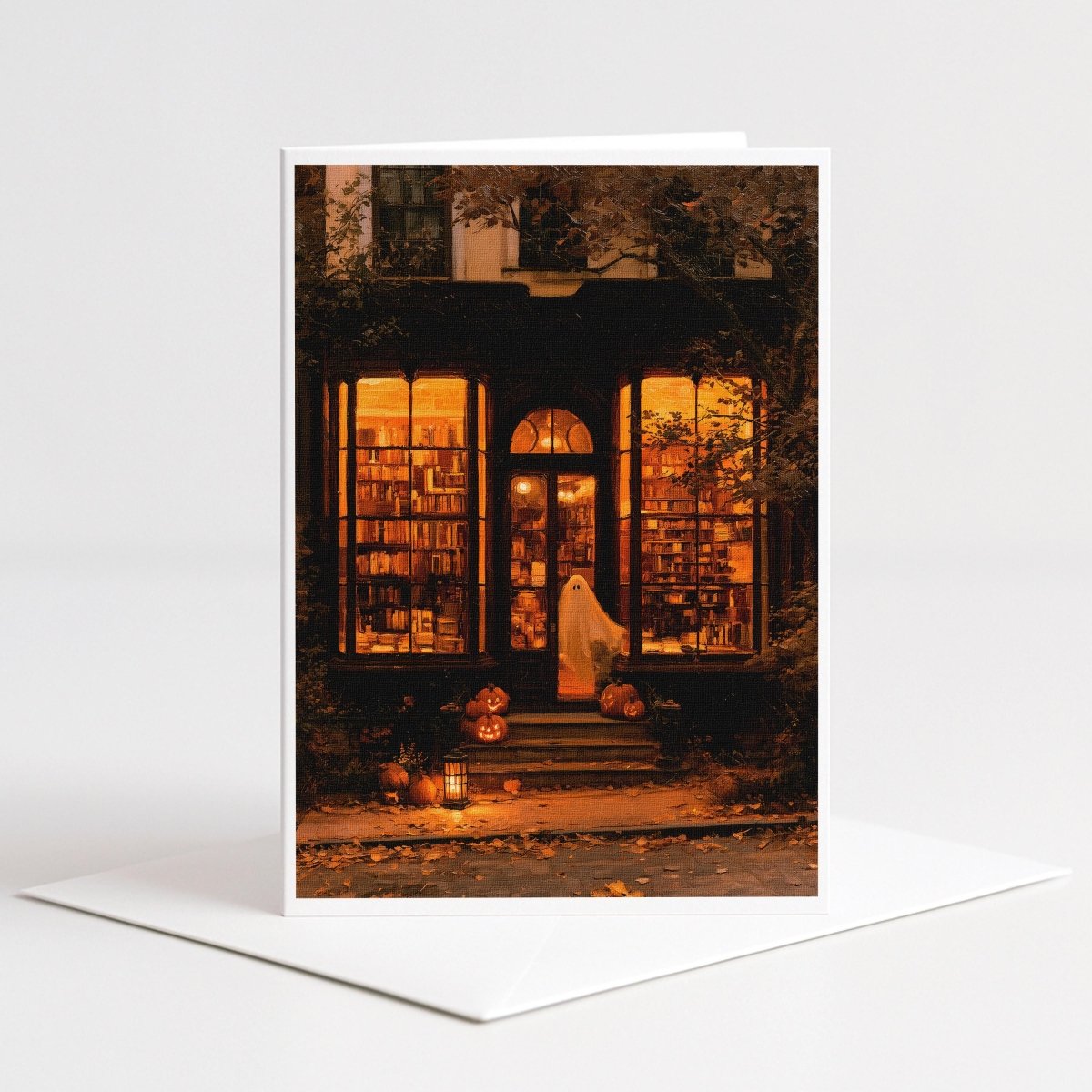 Haunted bookstore Halloween note card art of a ghostly figure at a glowing bookshop window with pumpkins and candles