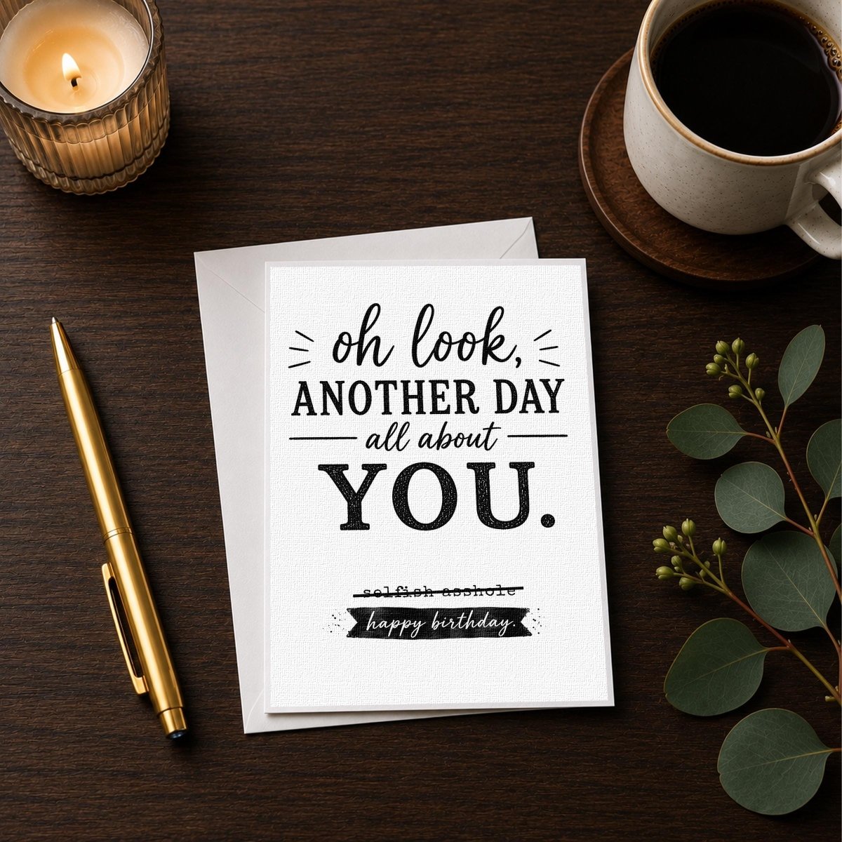 a birthday card with a humorous message, a candle, a pen, and a cup of coffee on a wooden surface.